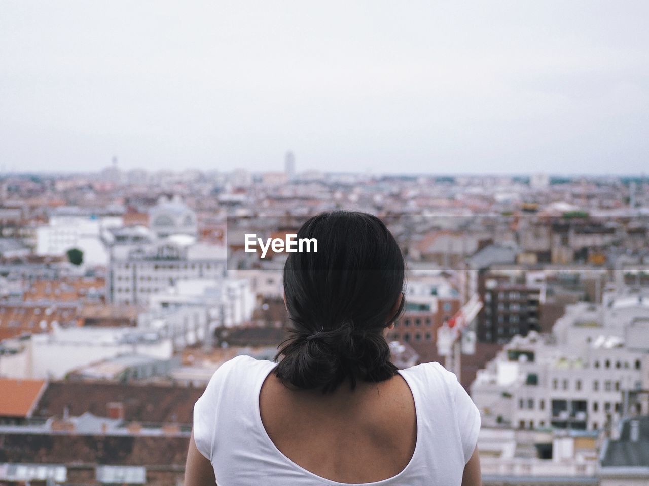 Rear view of woman looking at buildings in city against sky