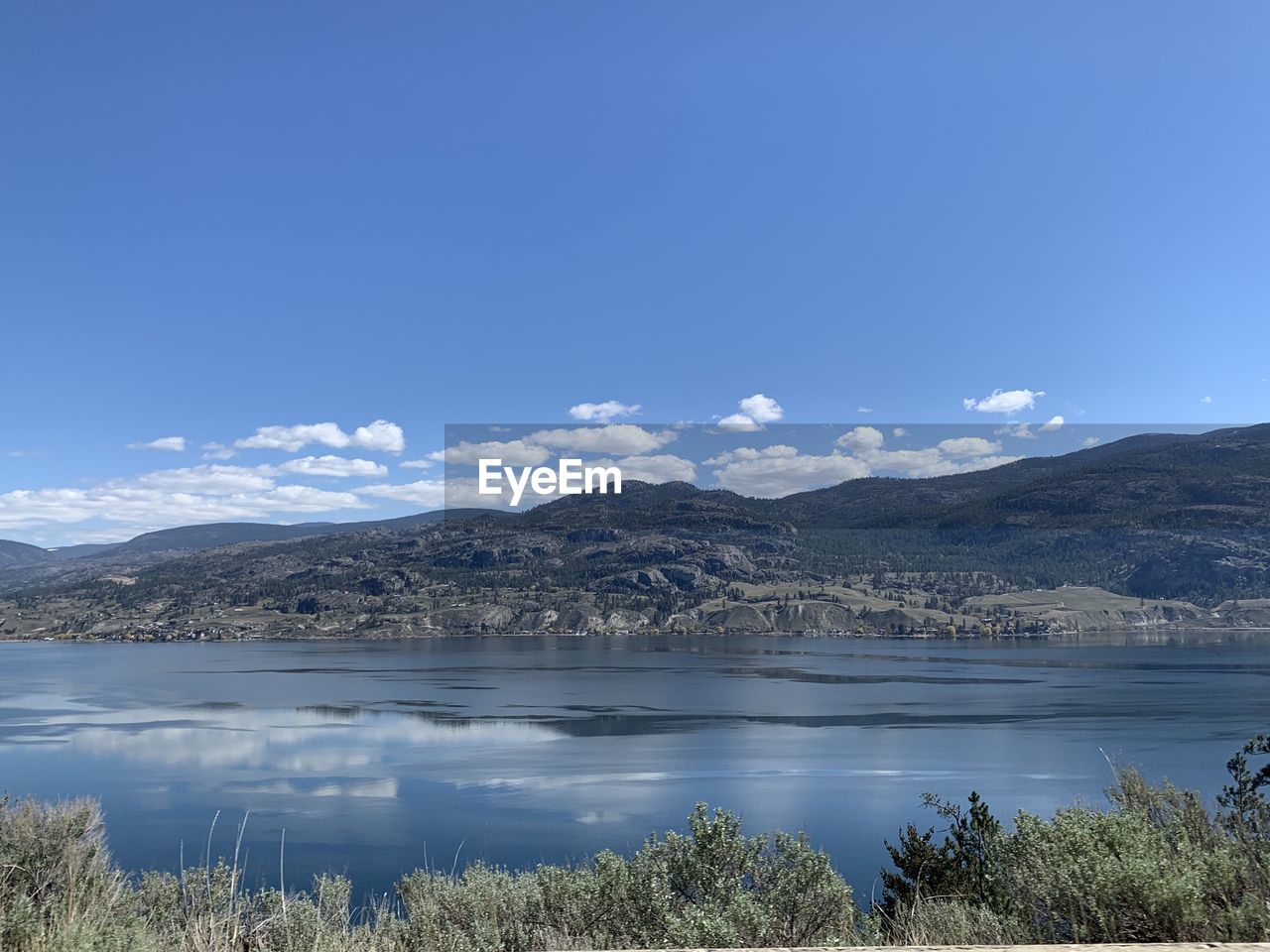 Scenic view of lake and mountains against blue sky