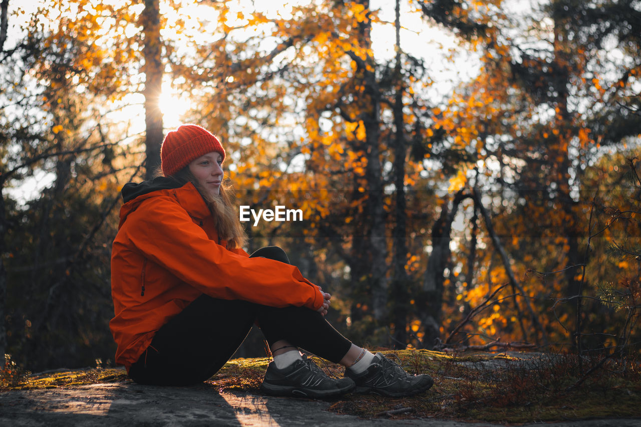 Traveller is sitting on top of a hill on a rock, resting after hard climb. vuokatti, kainuu finland.