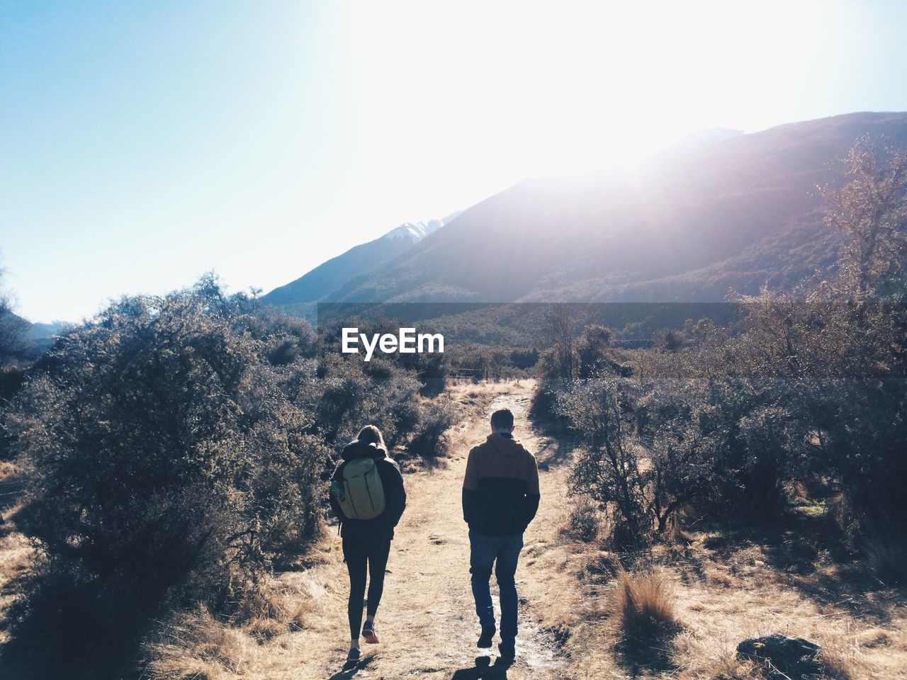 Rear view of couple walking through landscape on sunny day