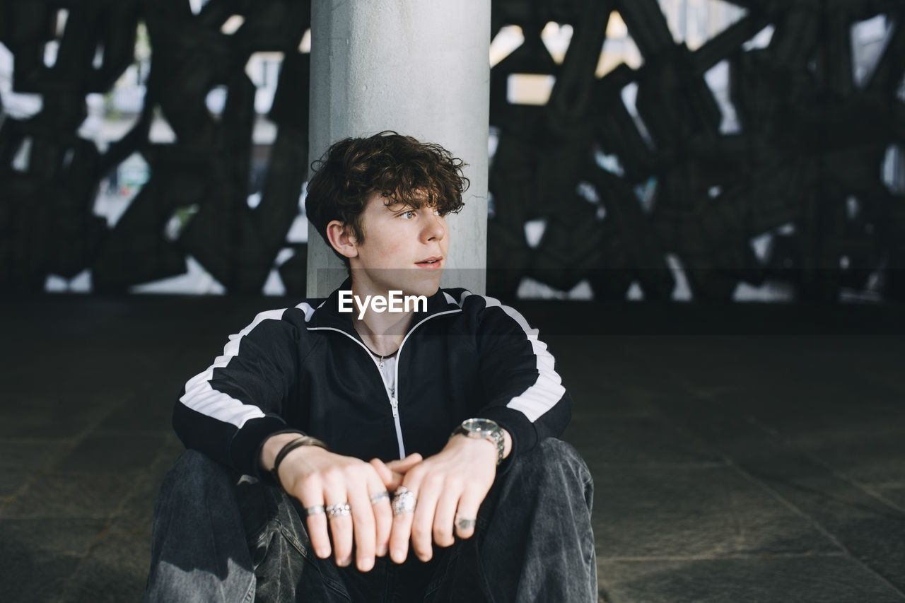 Teenage boy contemplating while sitting in parking garage