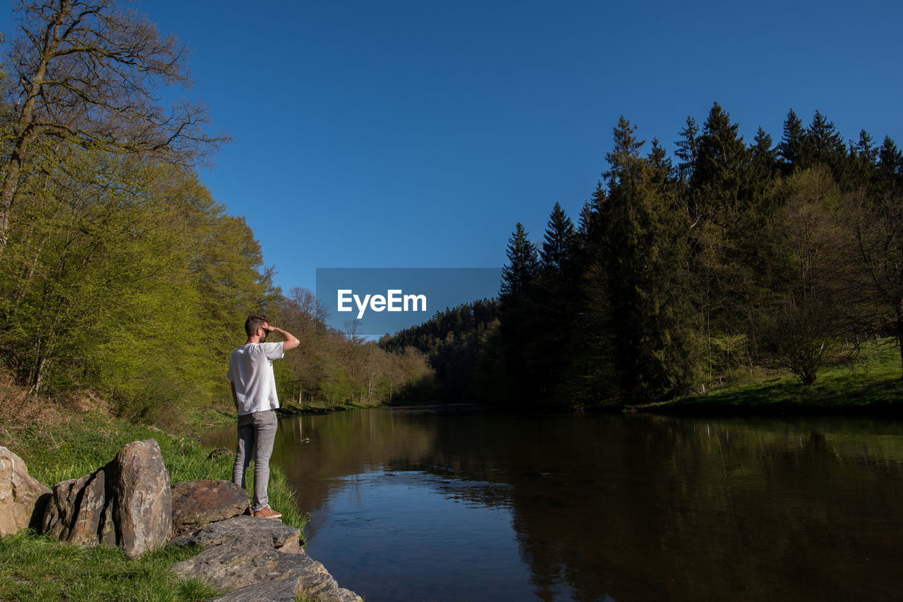 Young man standing by lake