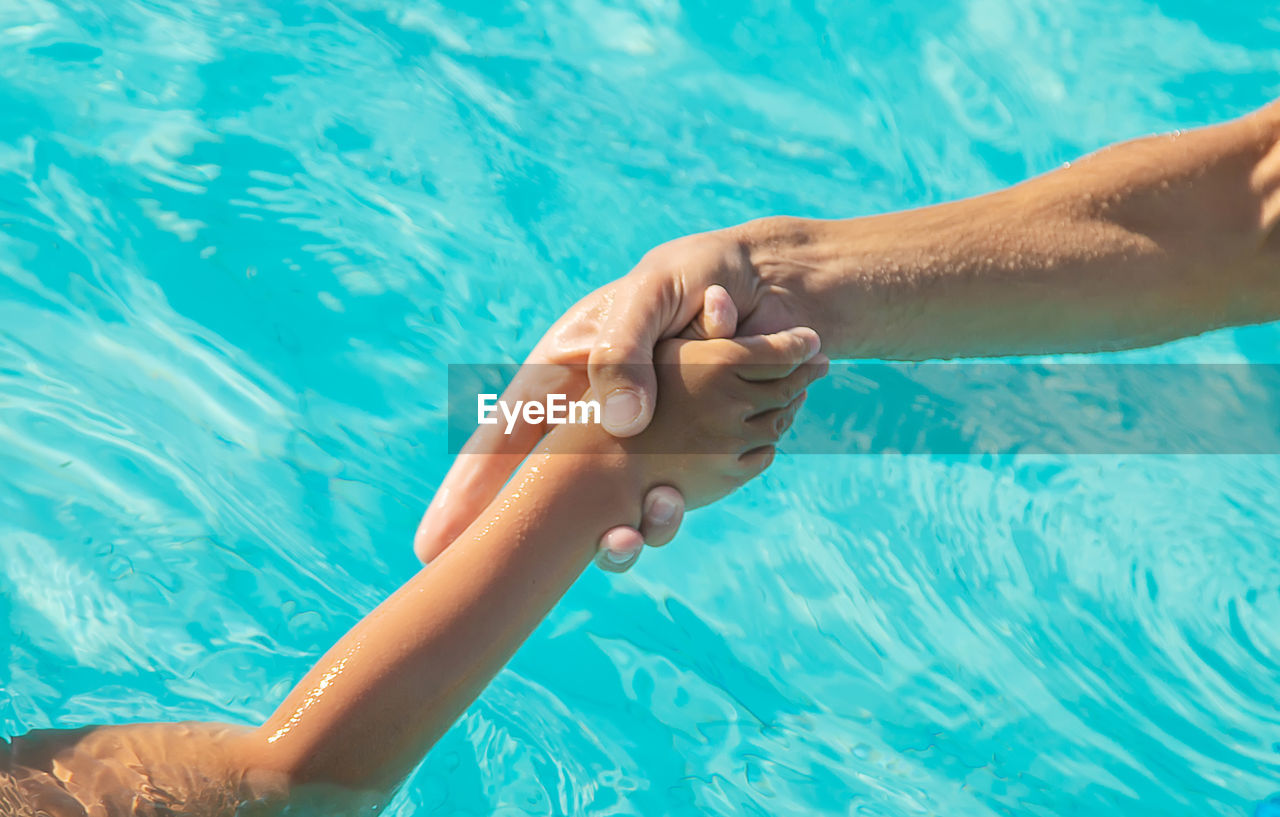 LOW SECTION OF WOMAN HAND IN SWIMMING POOL