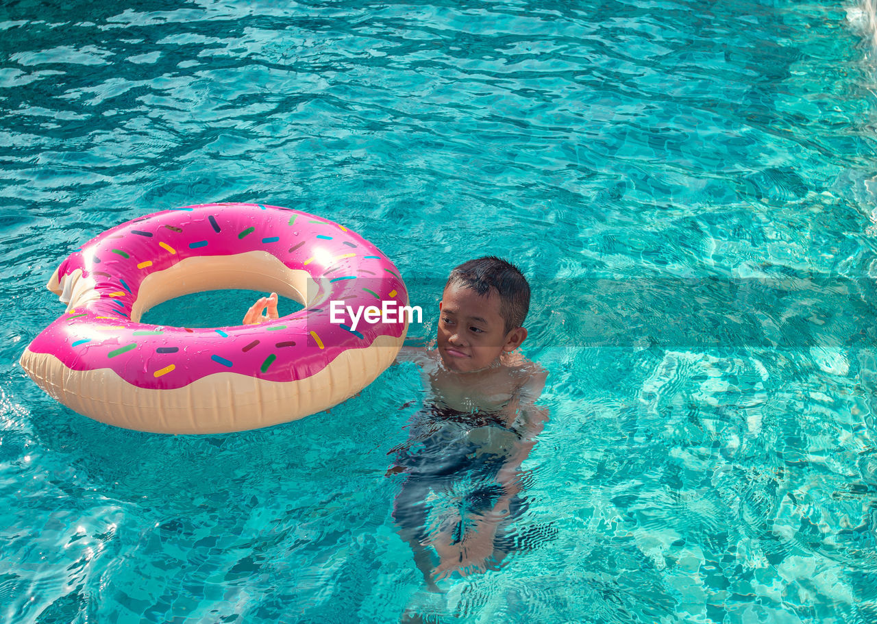 High angle view of boy swimming with inflatable in pool