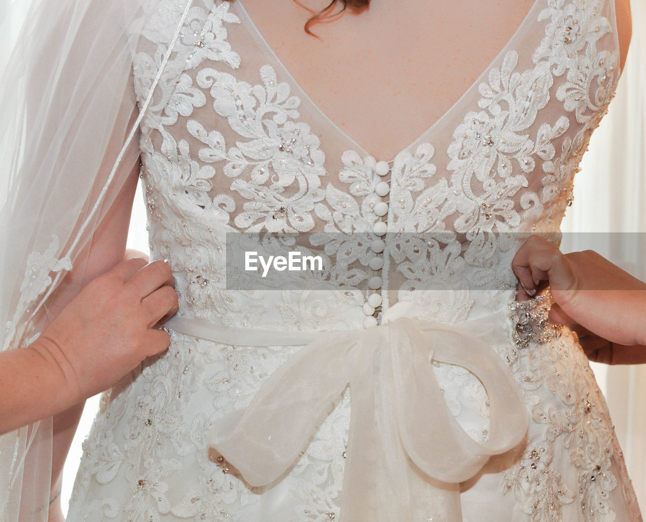 Cropped hands adjusting bride dress during wedding