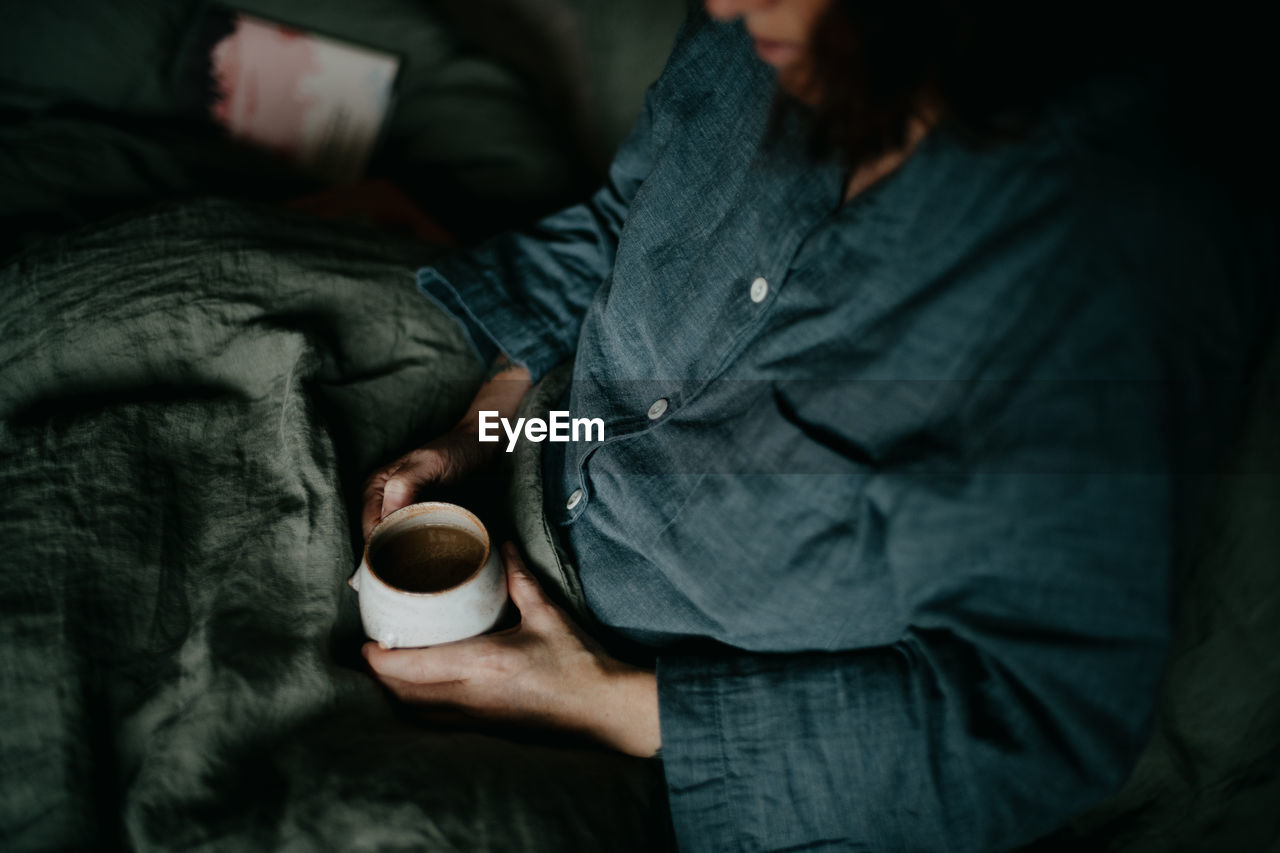 midsection of man holding coffee cup