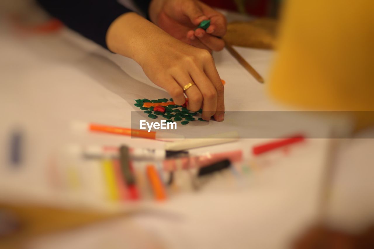 Close-up of human hand next to colored pencils