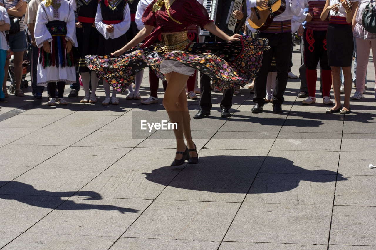 Low section of people in traditional clothing dancing on street in city