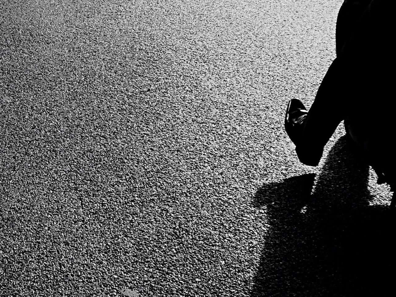 Low section of man on street during sunny day