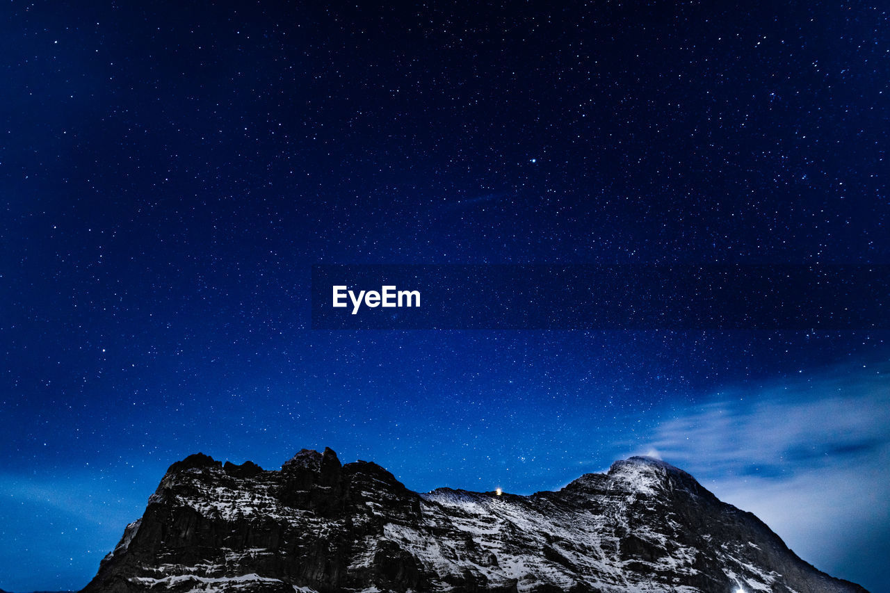 Low angle view of mountains against star field at night