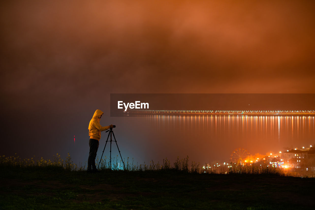 Man photographing against sky during sunset