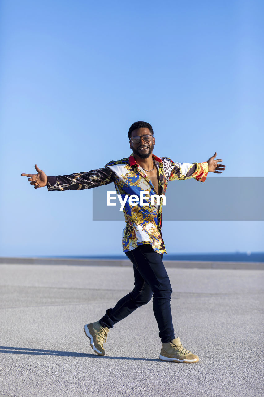 Full length portrait of man walking against blue sky