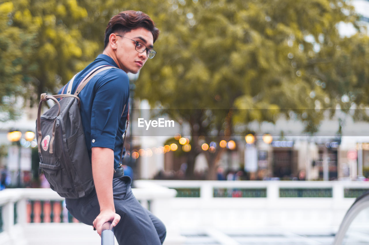 YOUNG MAN WALKING ON ROAD IN CITY