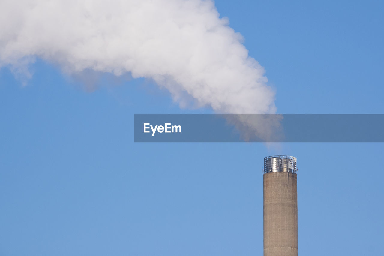 Smoke emitting from chimney against blue sky