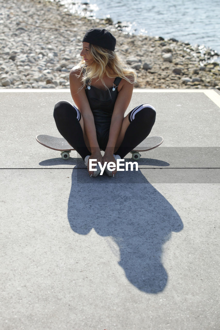 Woman sitting on skateboard at beach