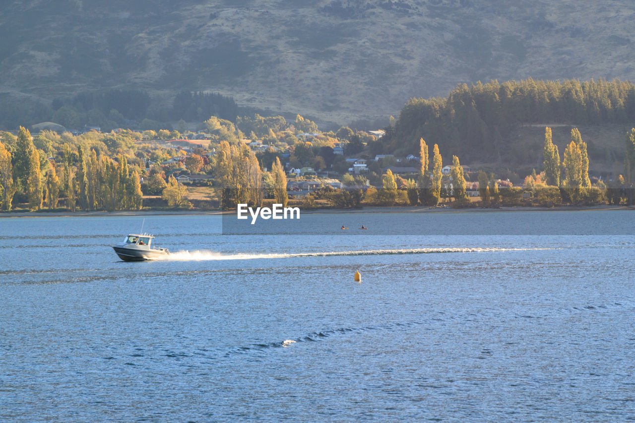 Sceneic view of lake with speed boat with mountains in the background