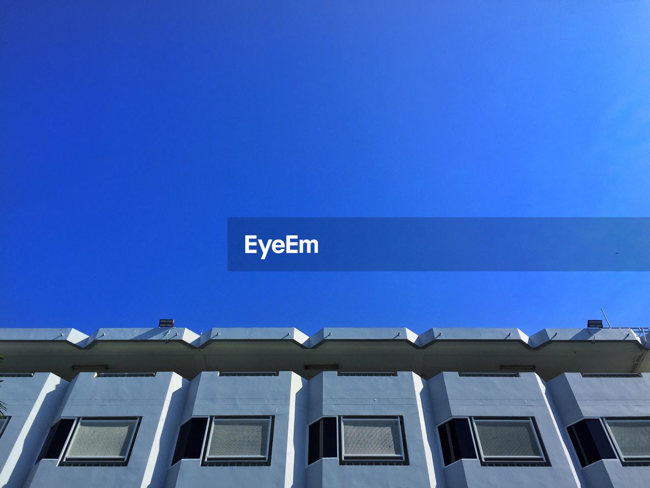 LOW ANGLE VIEW OF RESIDENTIAL BUILDING AGAINST CLEAR BLUE SKY