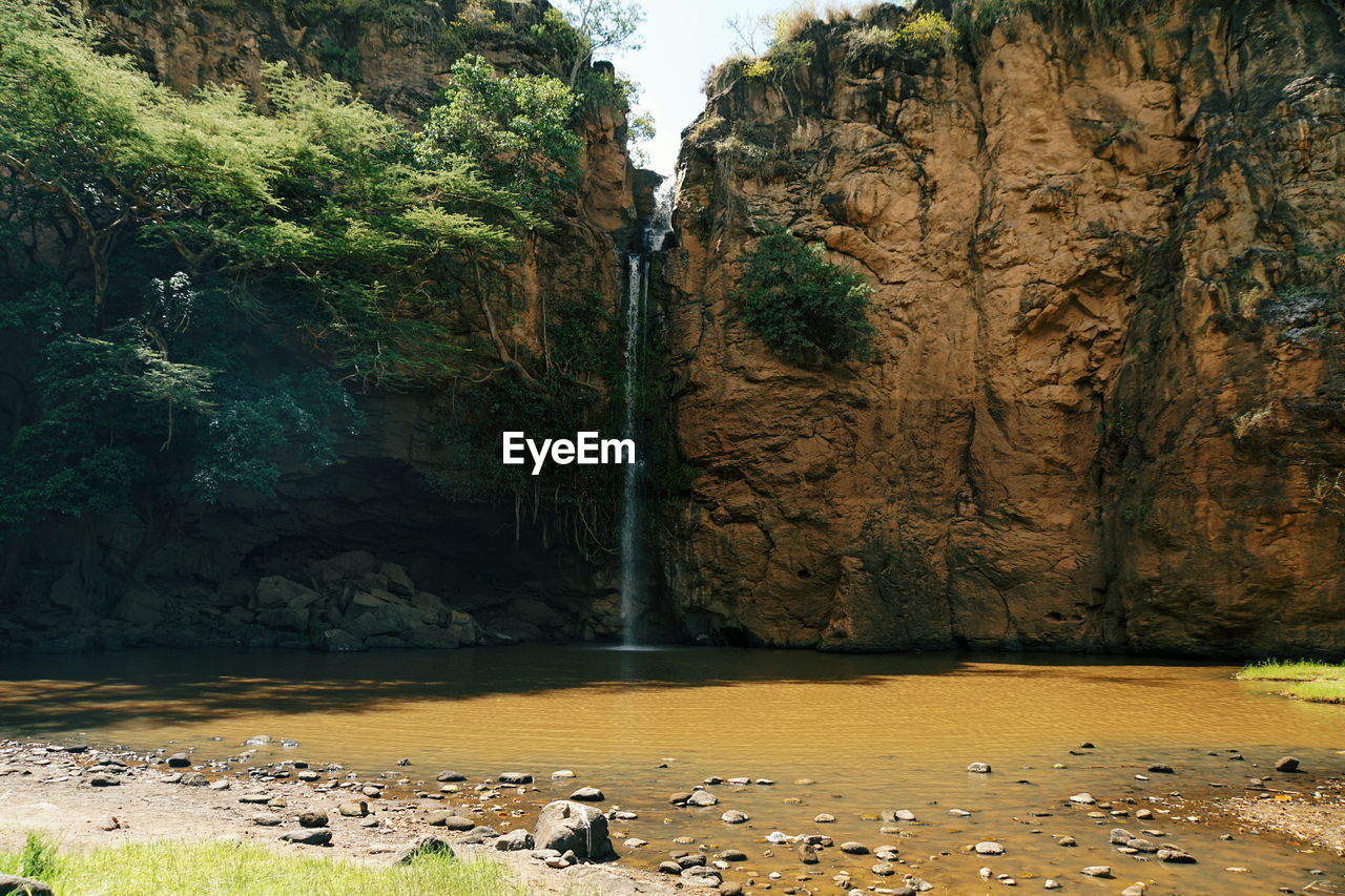 Scenic river against a rocky mountain background, makalia falls in lake nakuru national park, kenya 