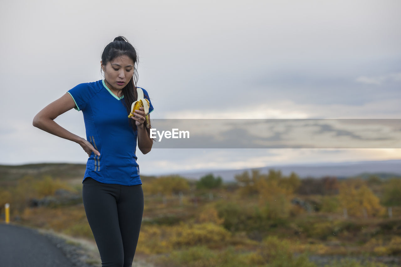 Beautiful woman eating banana during work out in rural area in iceland
