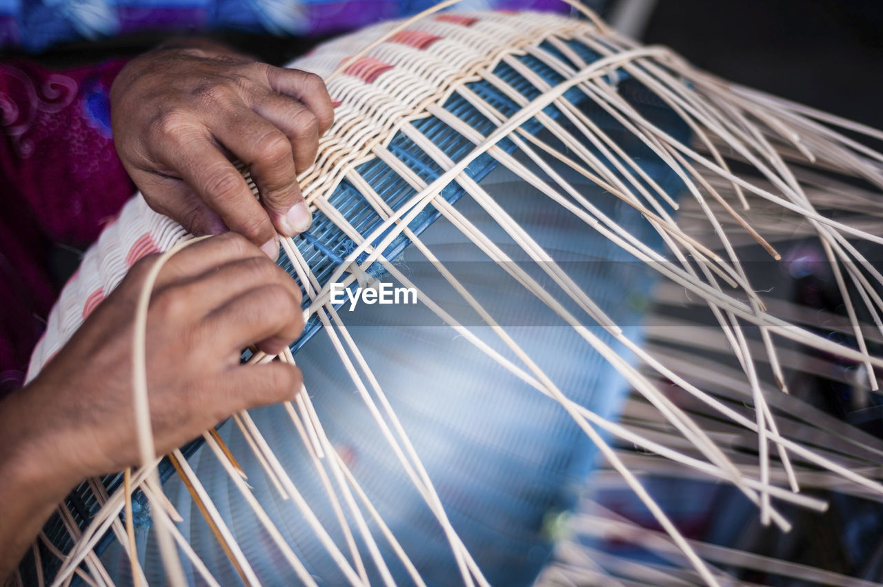 Cropped image of person weaving wicker basket