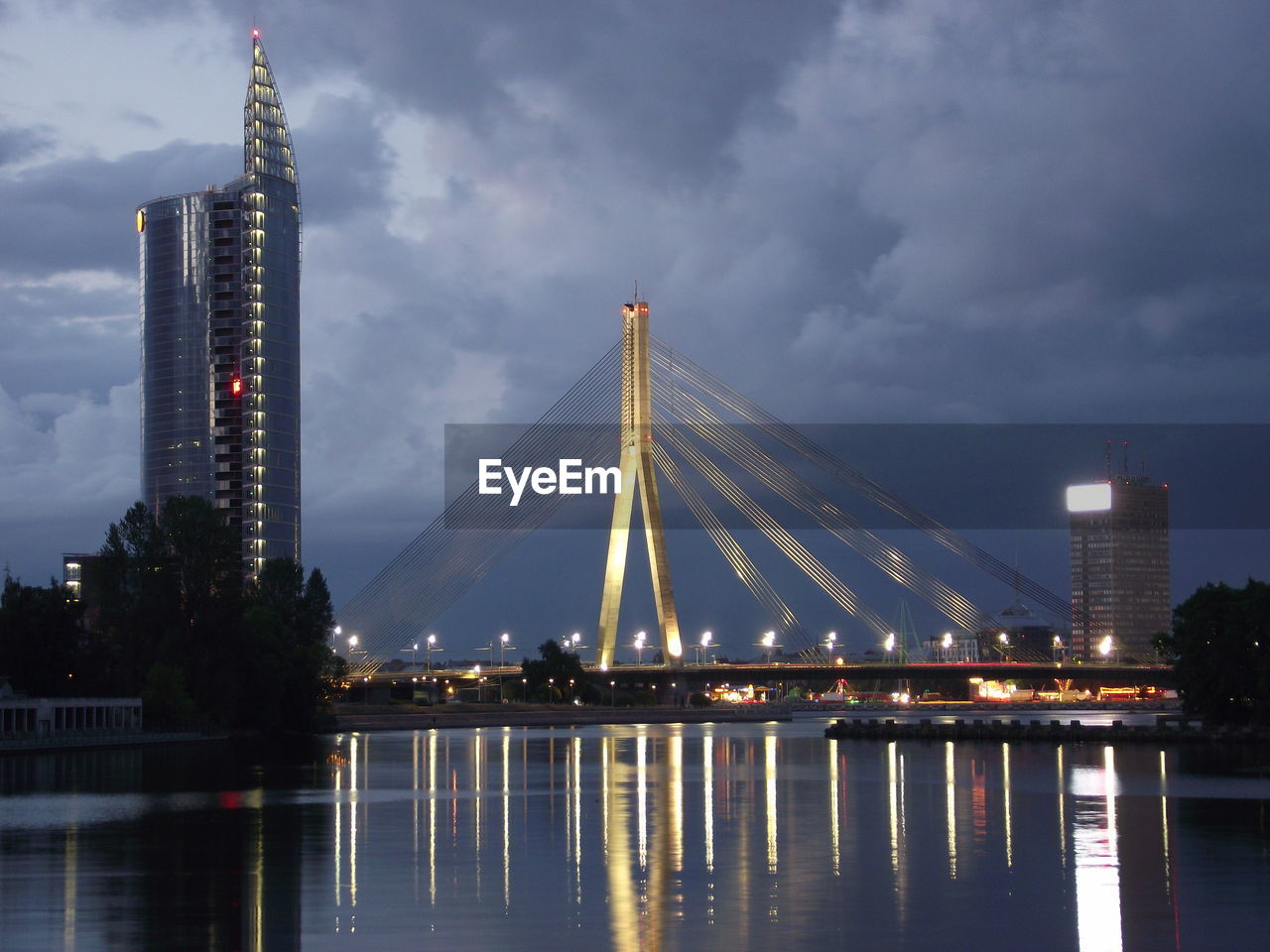 Illuminated bridge over river against sky in city