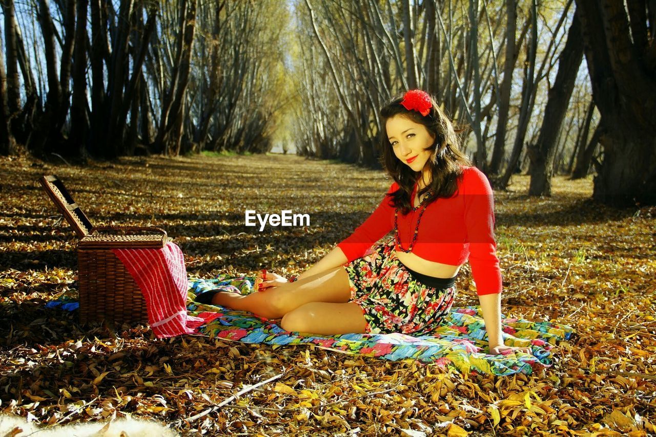 Portrait of beautiful woman sitting on field during autumn