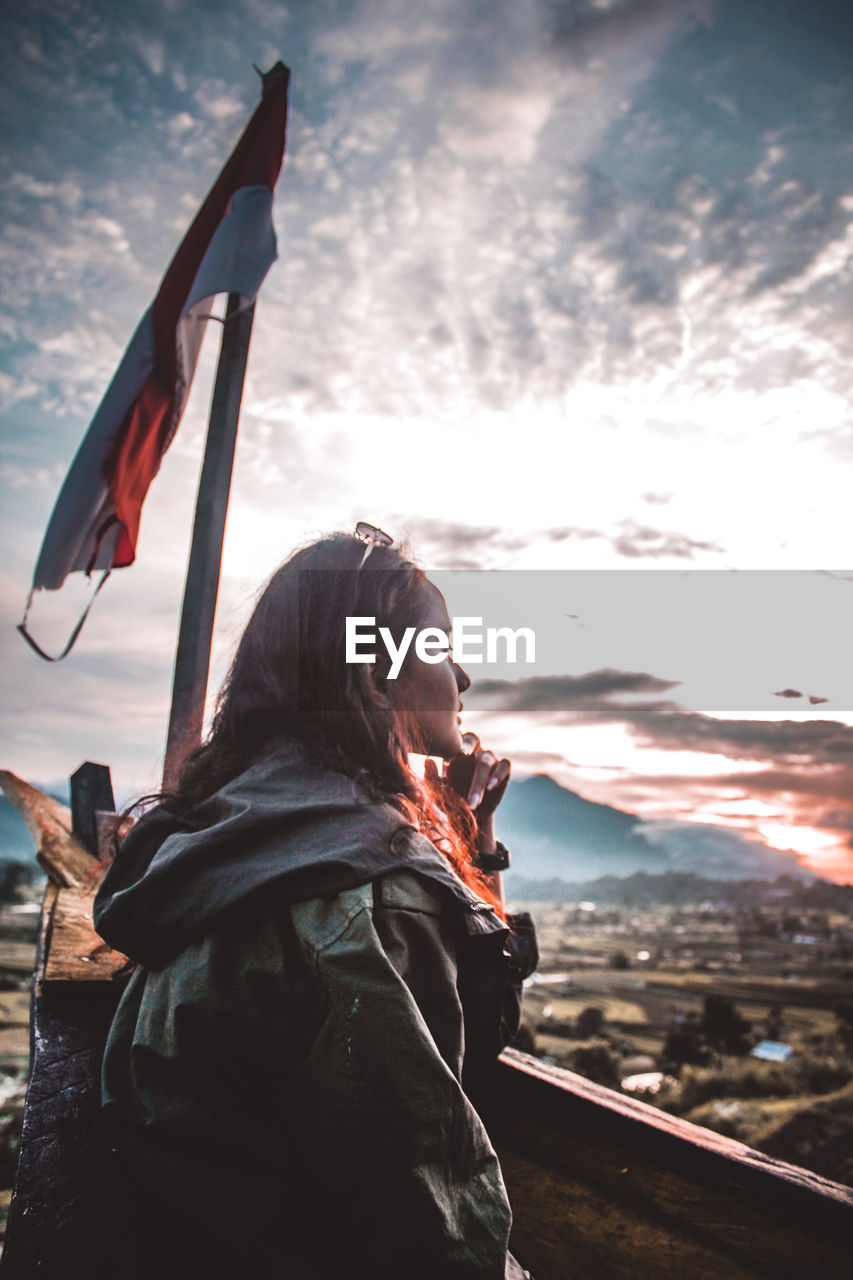 WOMAN LOOKING AT CAMERA AGAINST SKY