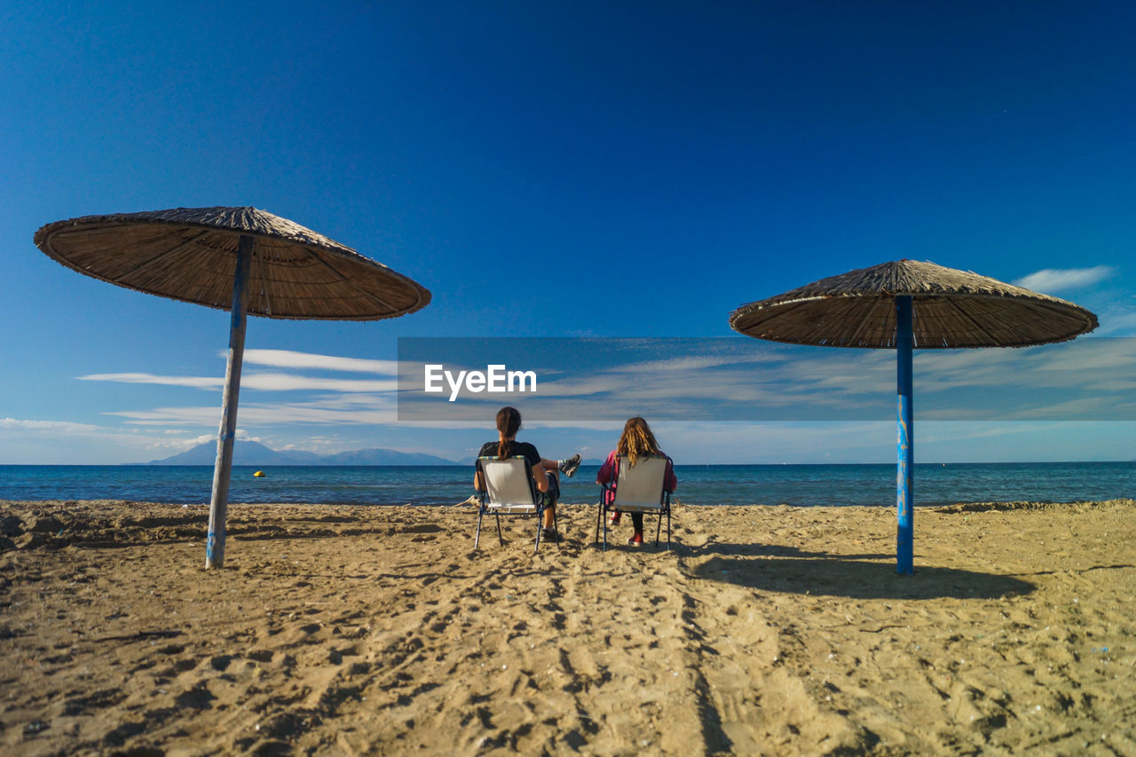 REAR VIEW OF PEOPLE ON BEACH