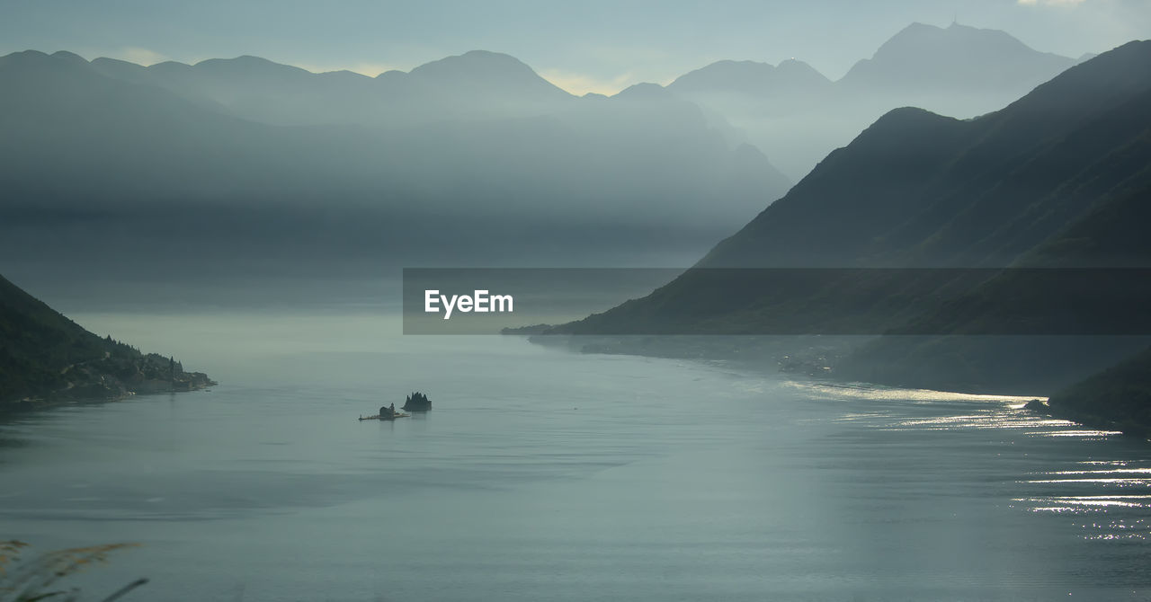 Scenic view of lake by mountains against sky