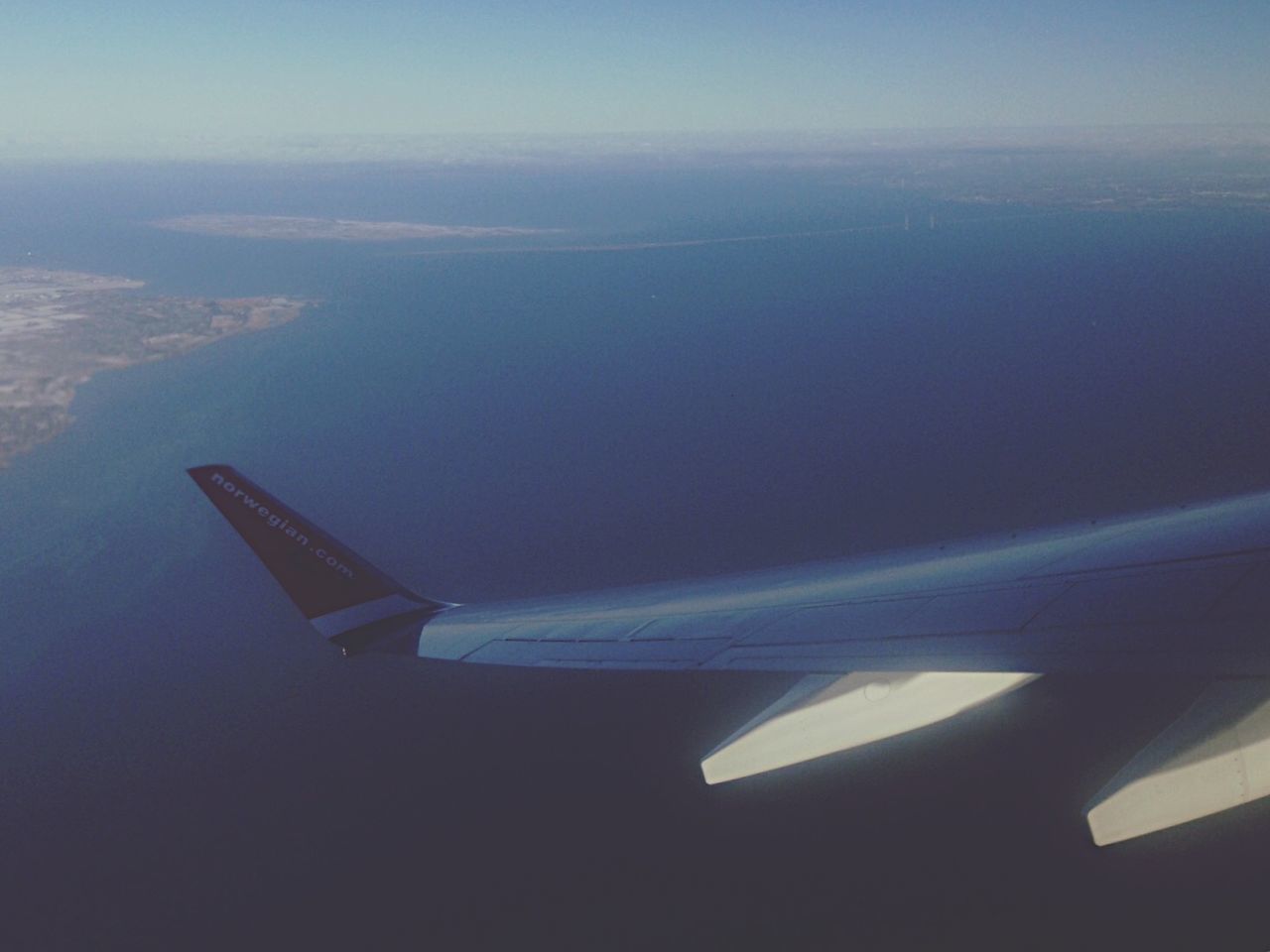 CROPPED IMAGE OF AIRPLANE WING OVER CLOUDS