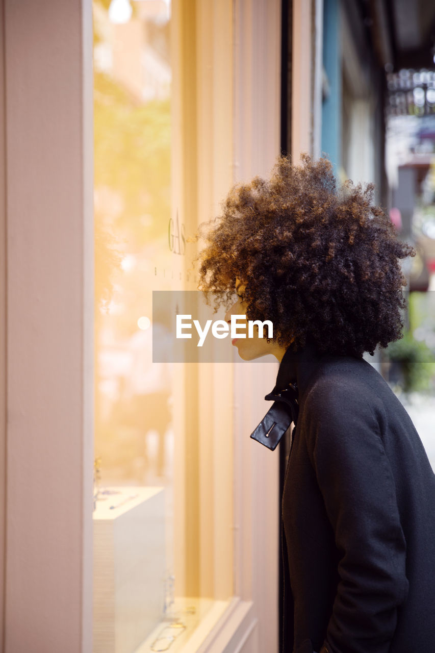 Side view of woman window shopping in city