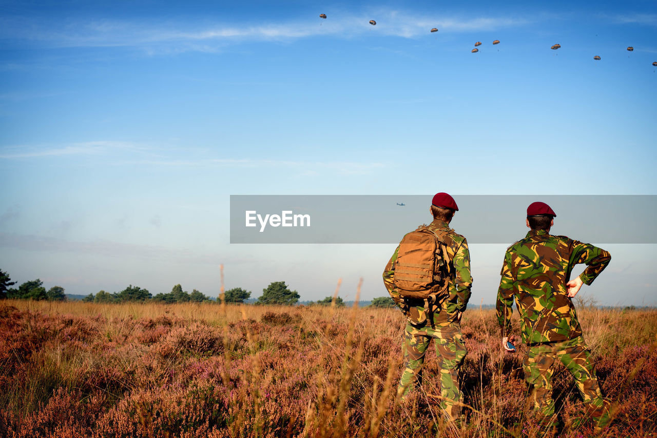 Rear view of soldiers standing on field