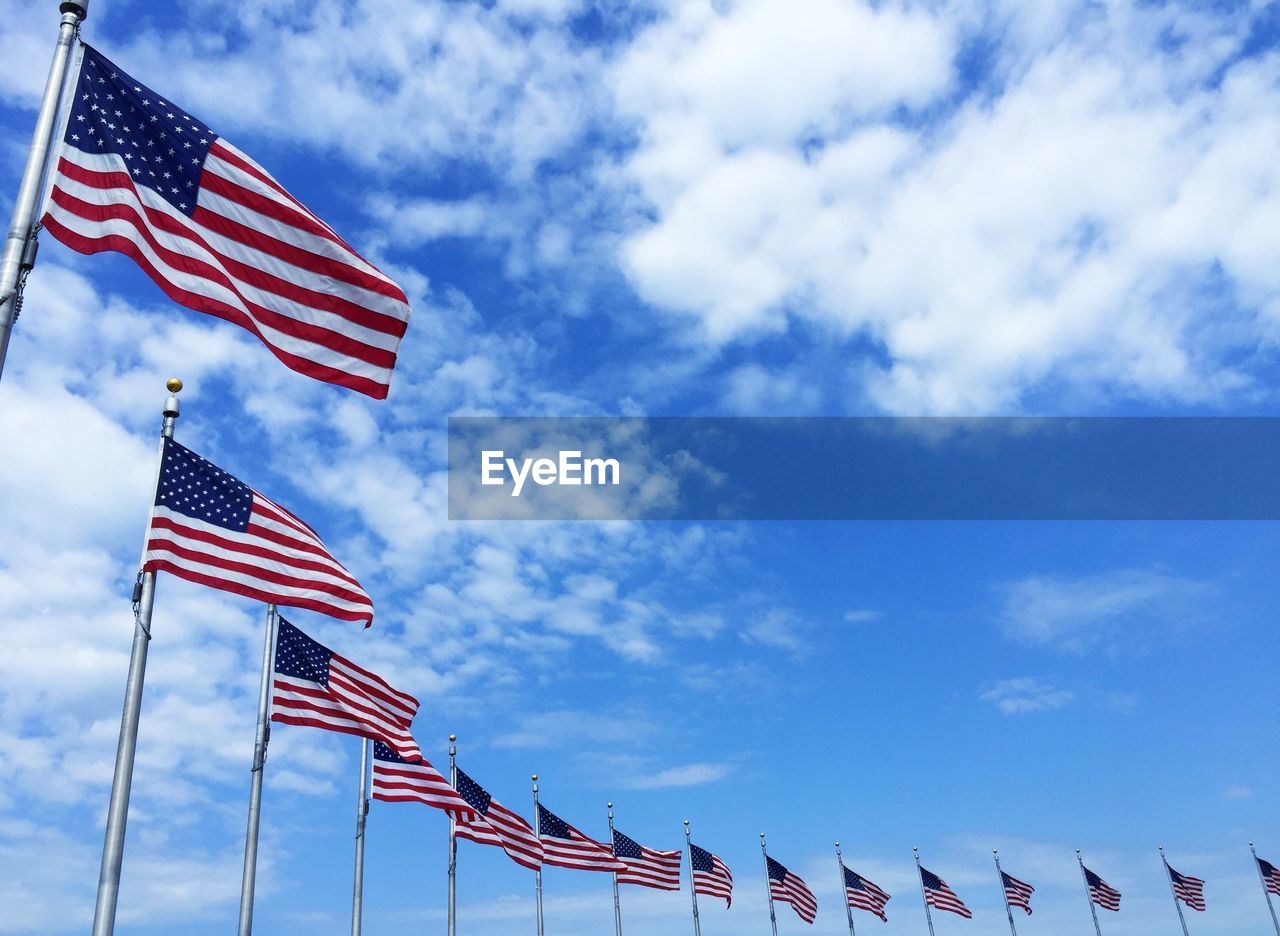 Low angle view of american flags around washington monument against sky