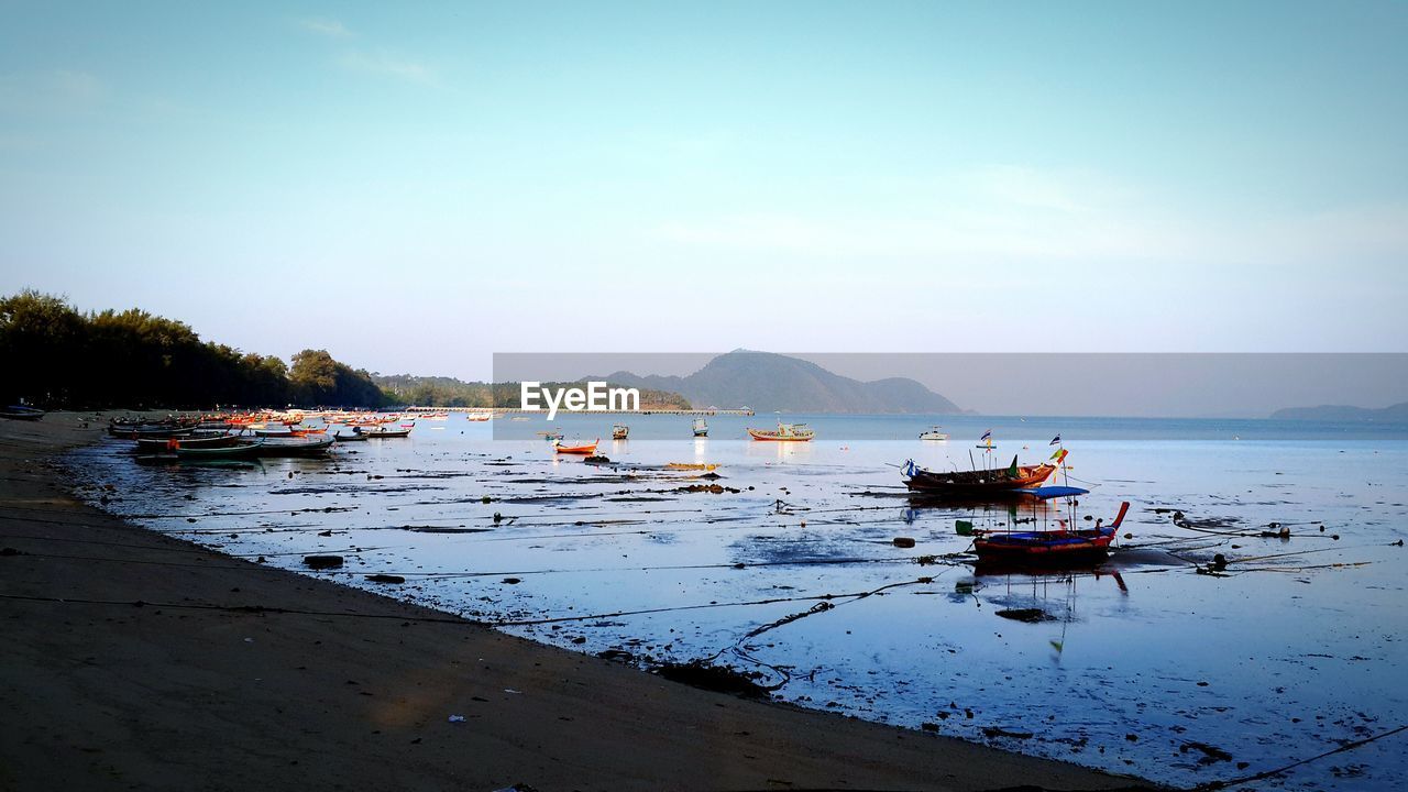 Boats moored at beach against sky