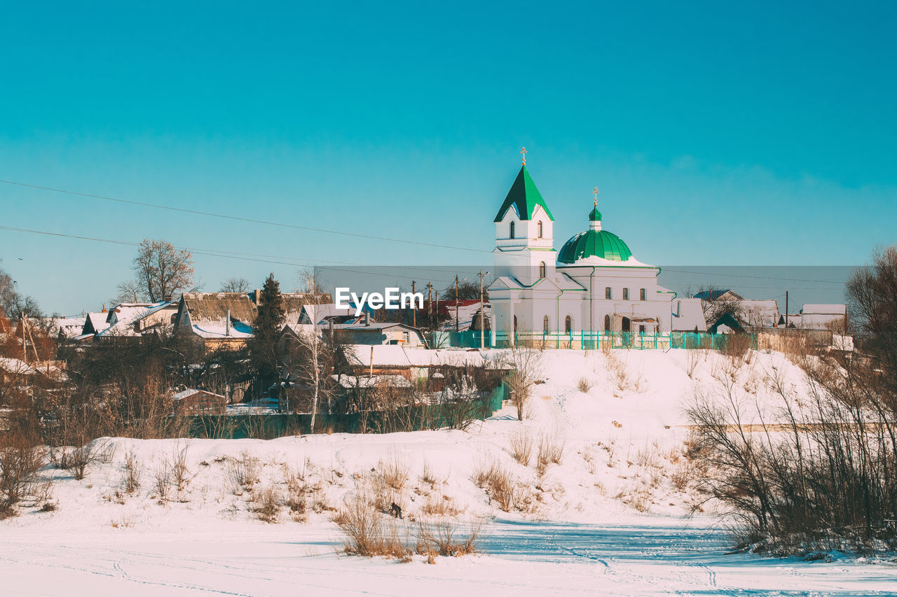 BUILDINGS AGAINST CLEAR BLUE SKY DURING WINTER AGAINST THE BACKGROUND