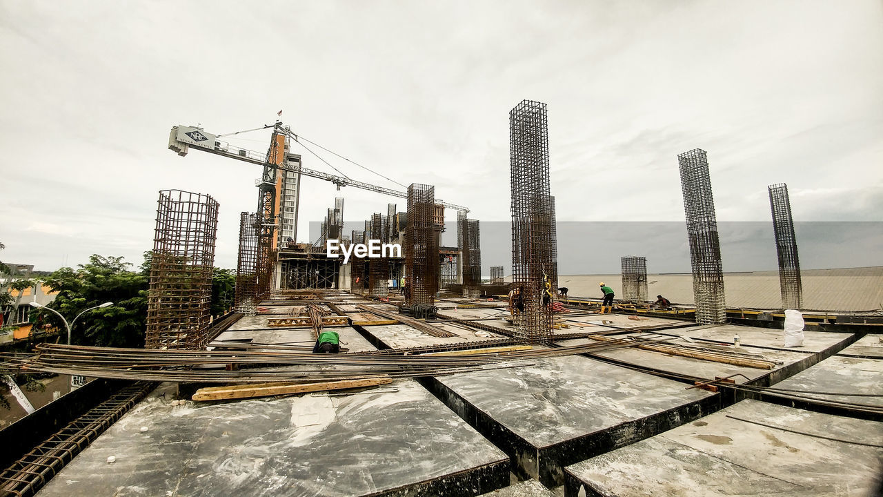 Cranes at construction site against sky in city