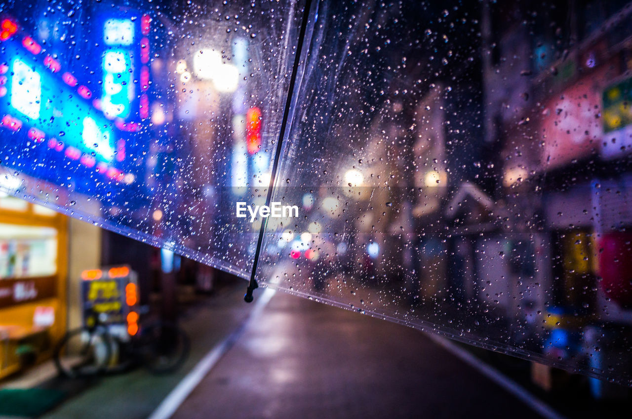 Cropped image of wet umbrella during rainy season on street at night