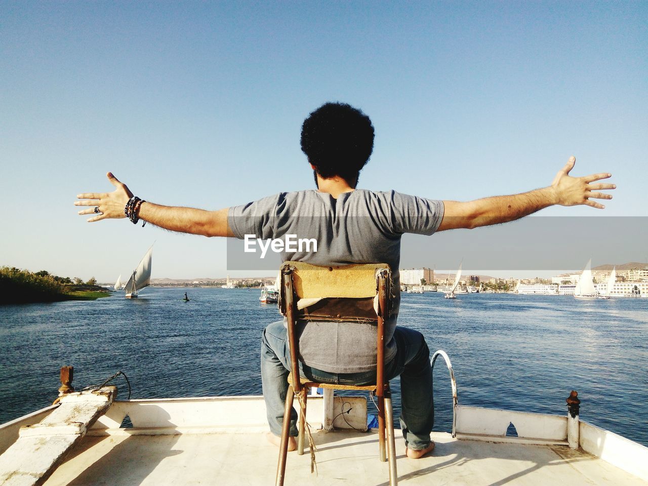 Rear view of man sitting on chair in boat