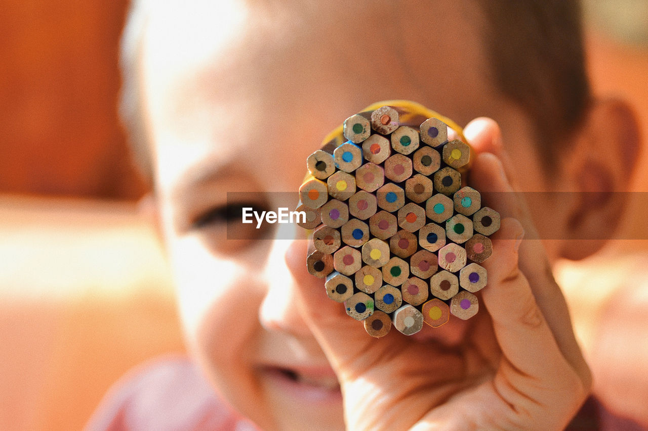 Close-up portrait of boy holding colored pencils