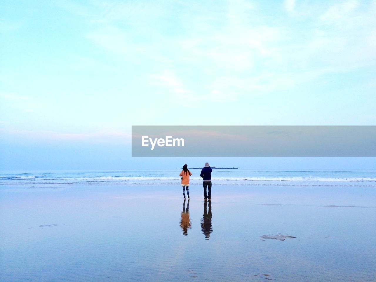 Rear view of people against sky on beach