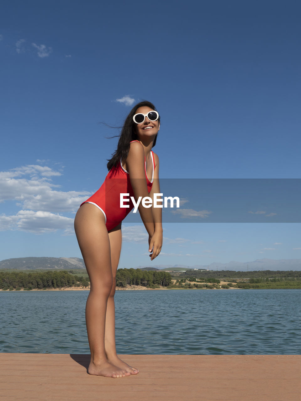 Portrait of young woman in bikini standing at beach against sky