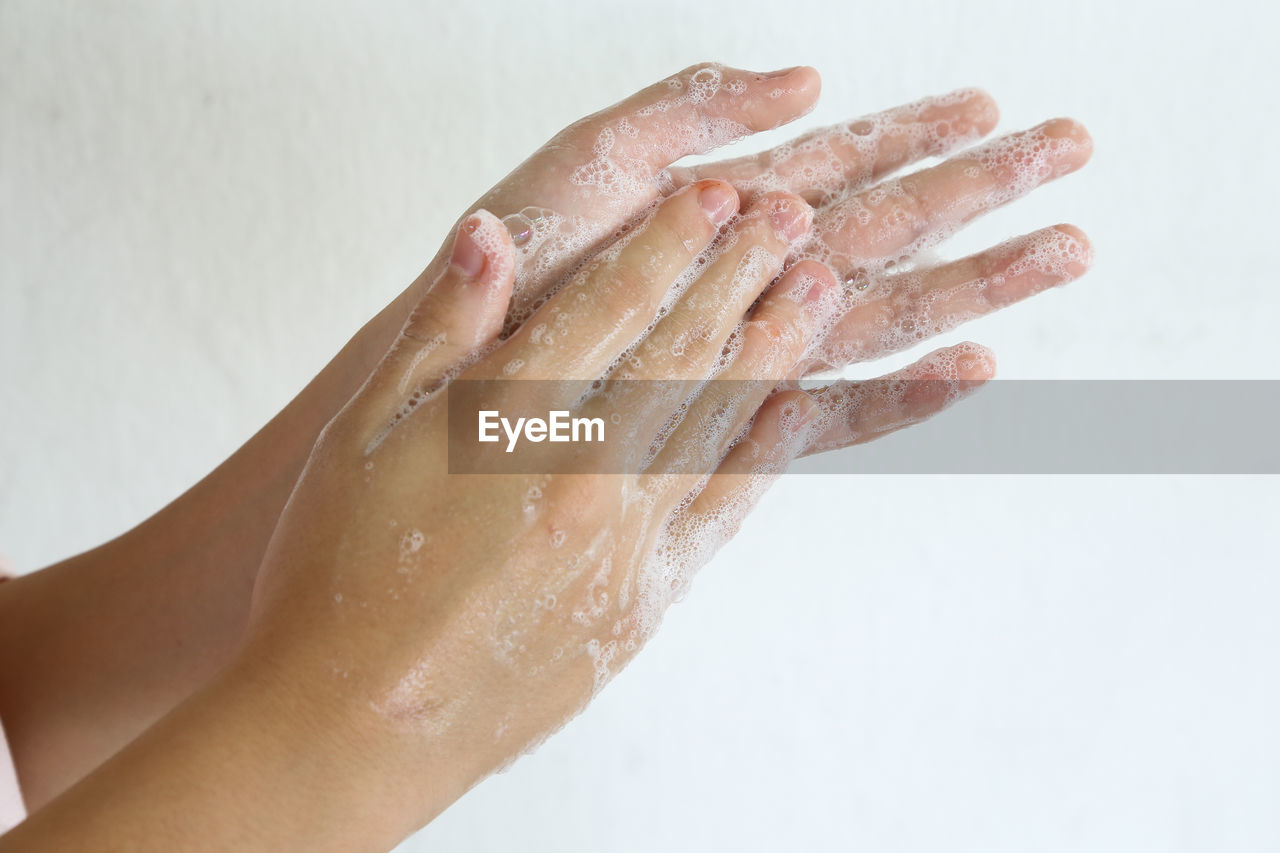 Close-up of hand washing against white background