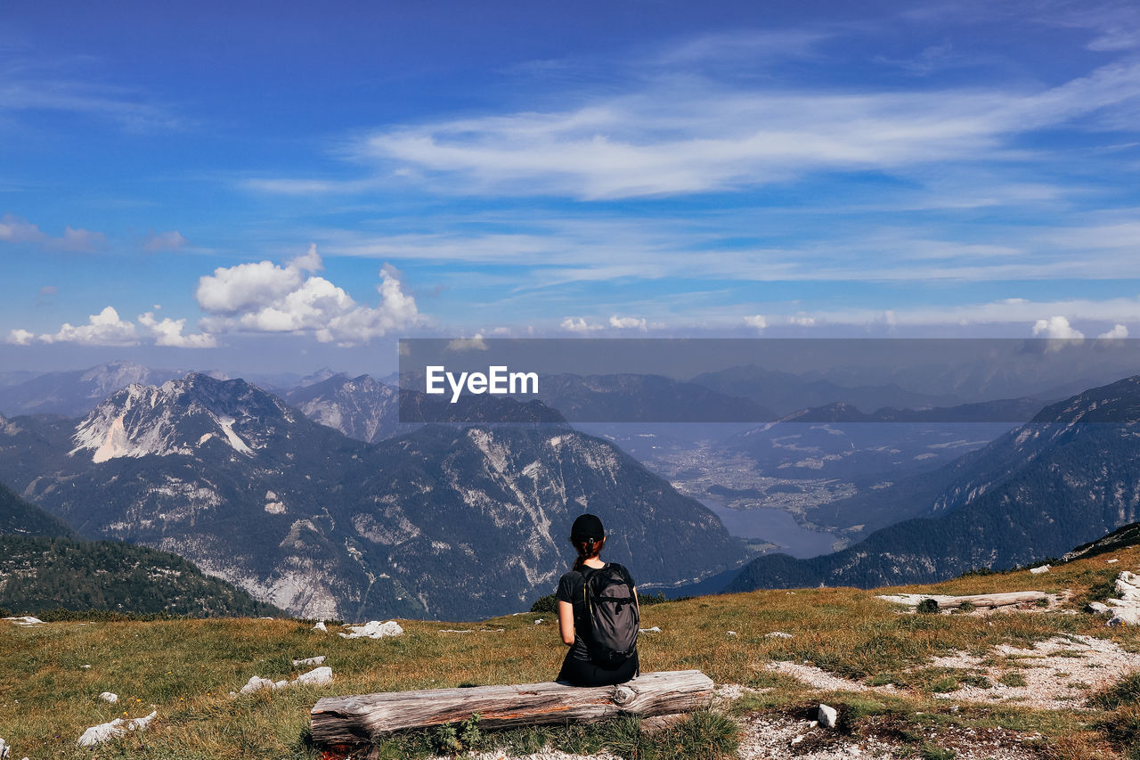 Man sitting on mountain against sky