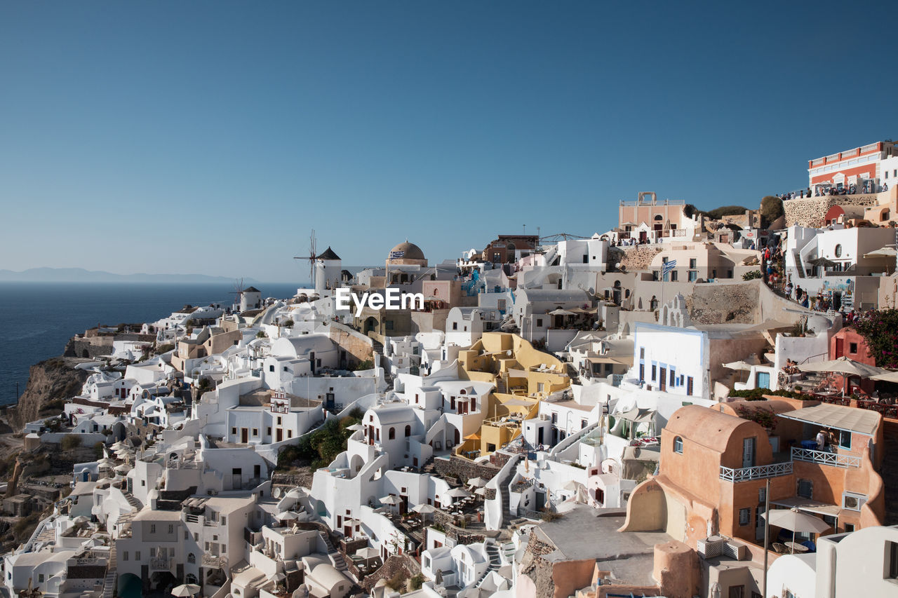 AERIAL VIEW OF TOWNSCAPE BY SEA AGAINST BLUE SKY