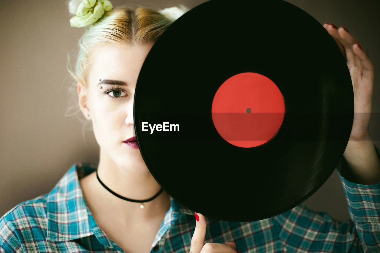 Portrait of young woman holding vinyl record while standing at home