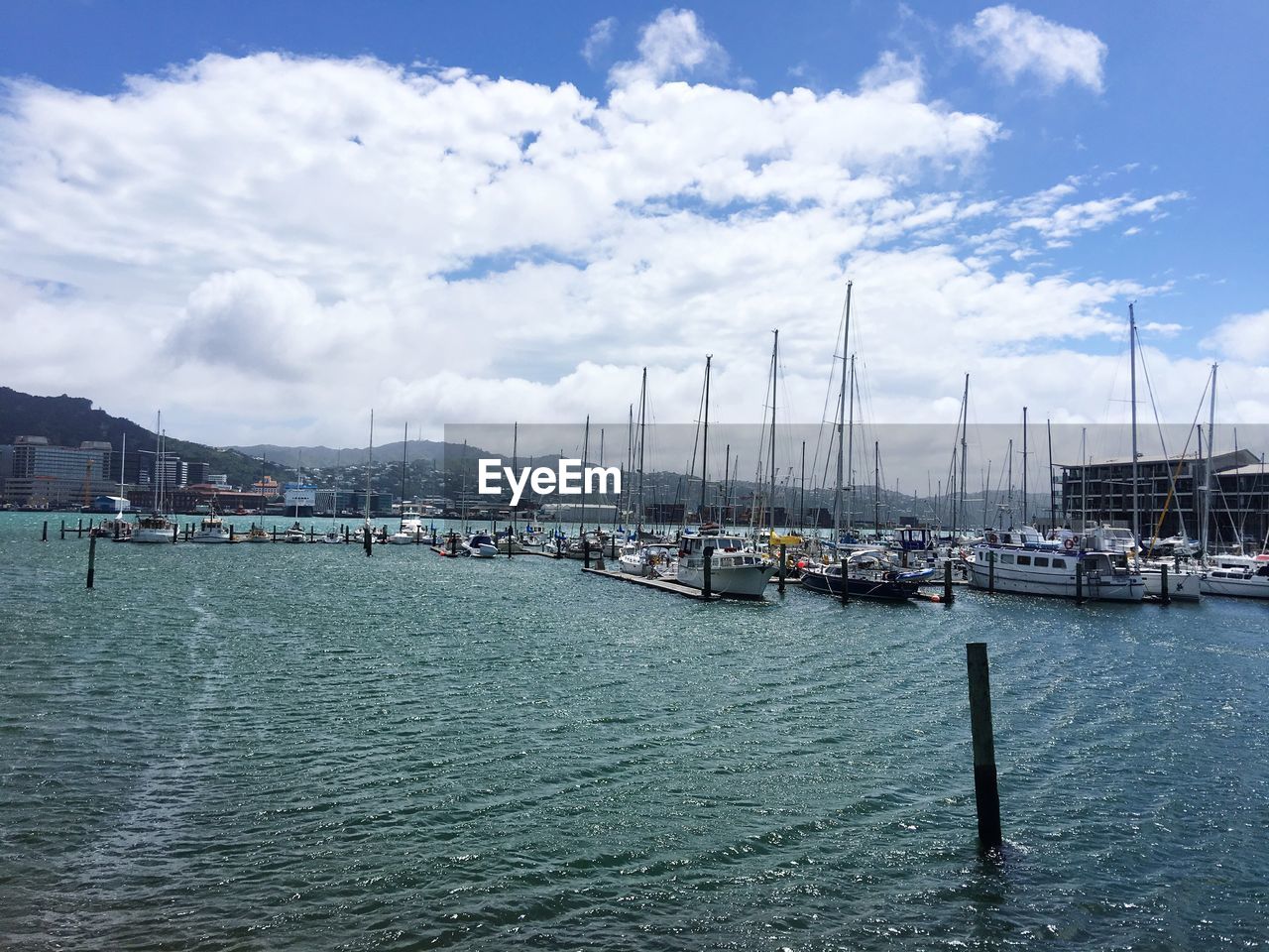 SAILBOATS MOORED IN HARBOR AGAINST SKY