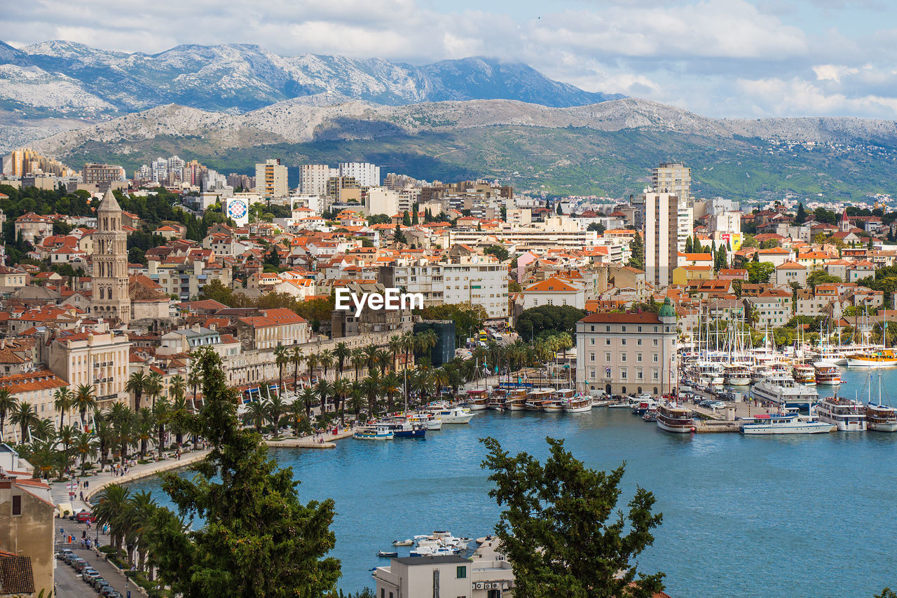 Cityscape at sea shore against mountains