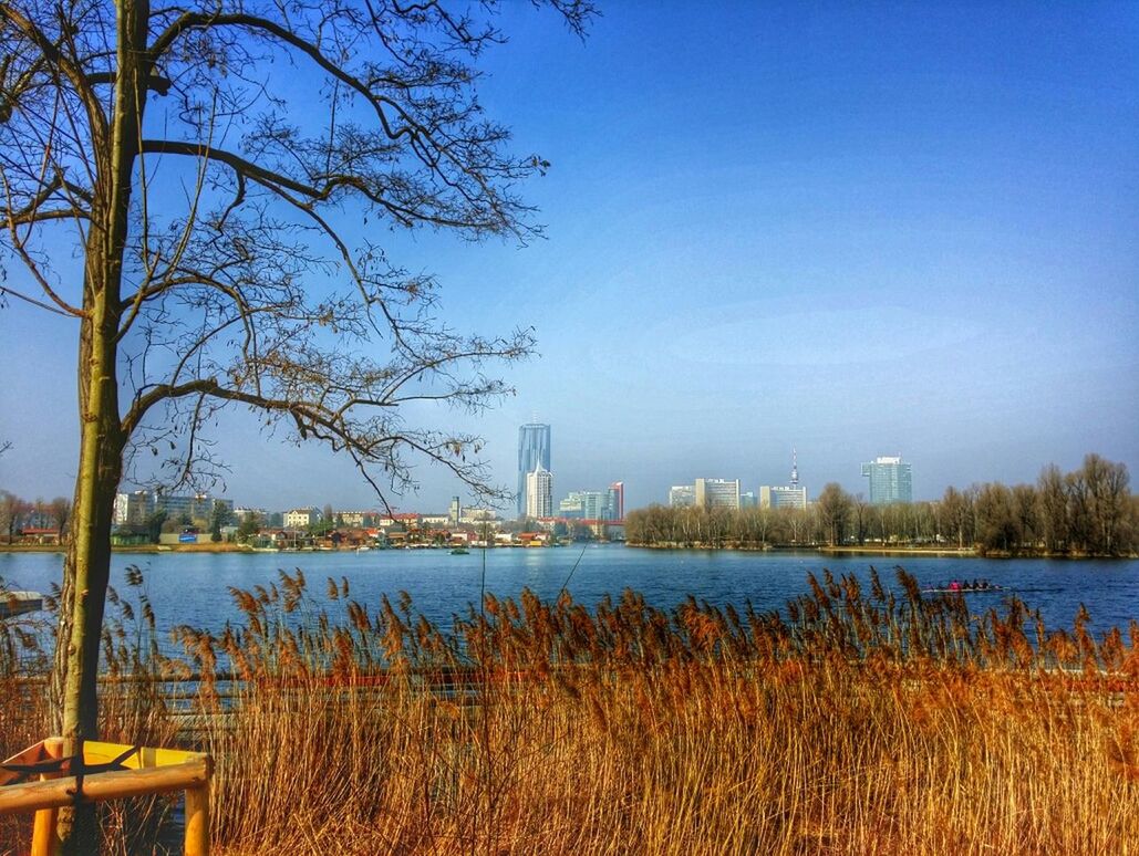 VIEW OF CALM RIVER WITH BUILDINGS IN BACKGROUND