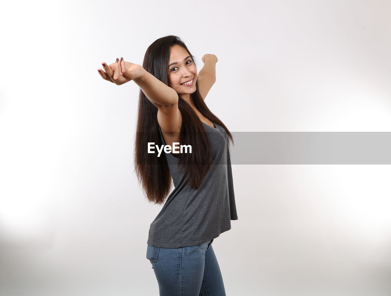 YOUNG WOMAN STANDING AGAINST WHITE BACKGROUND