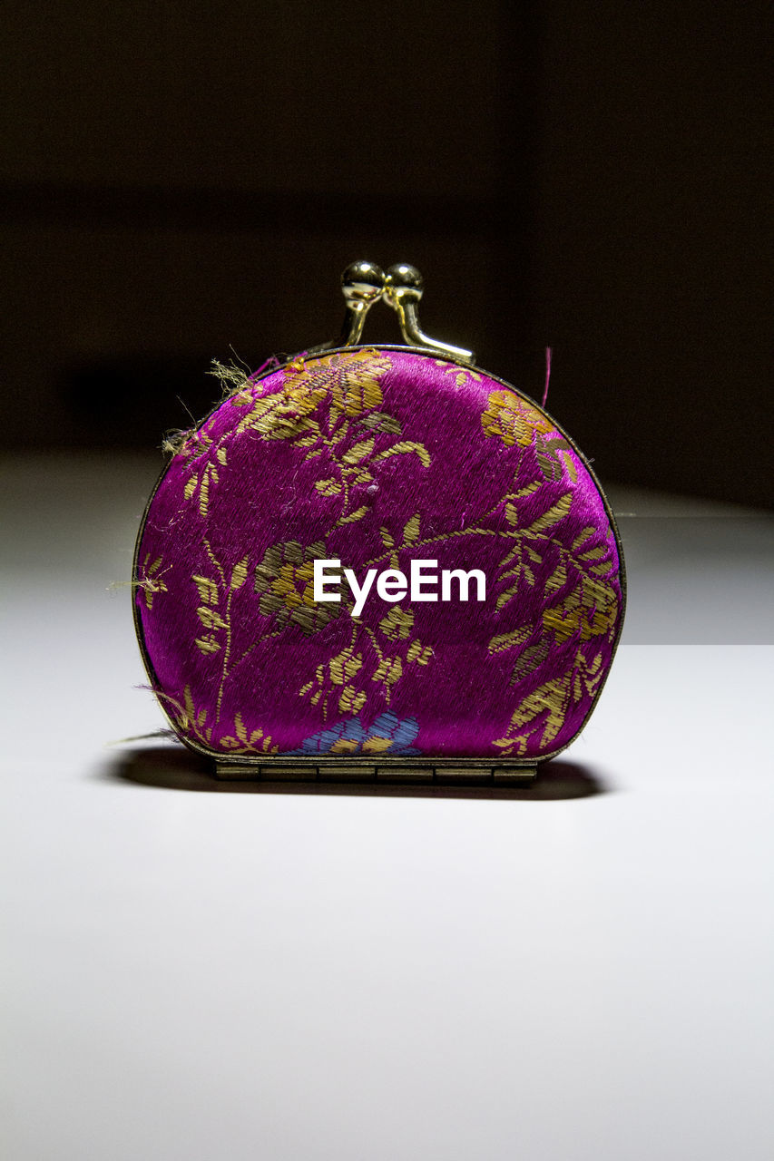 Close-up of purse on table against black background